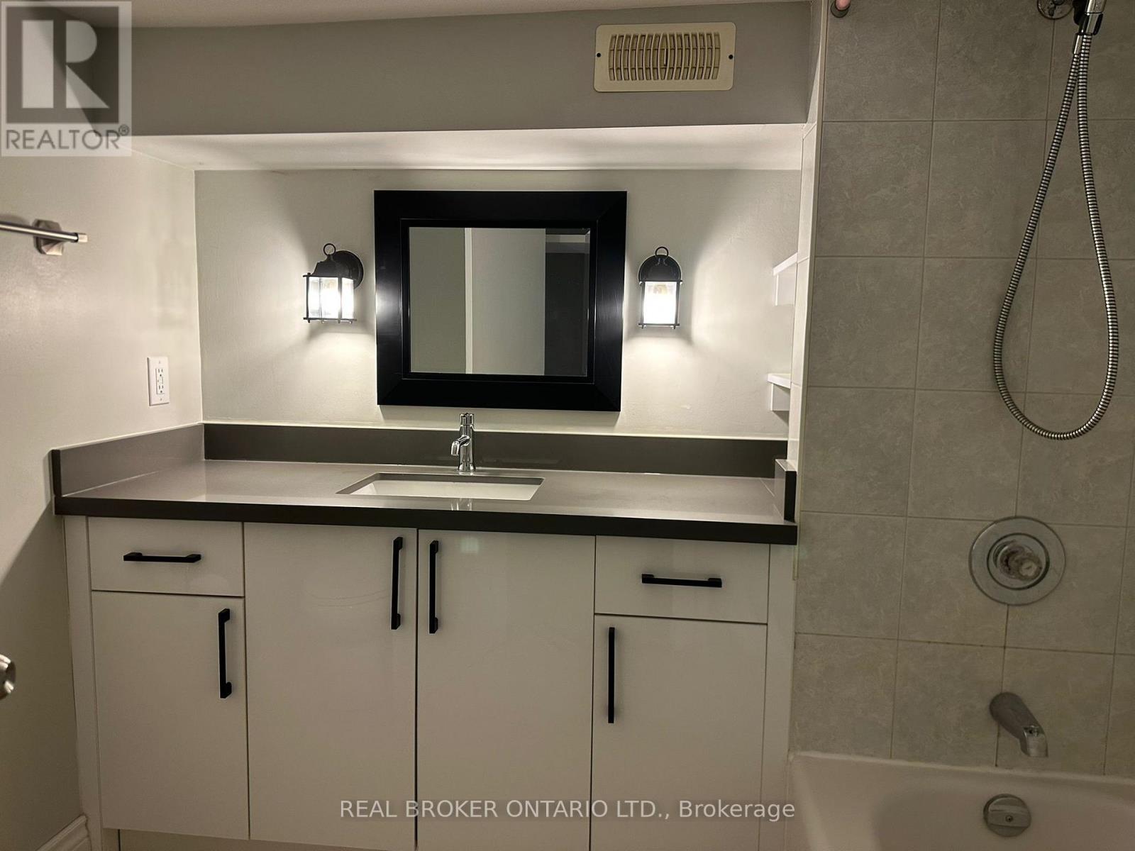 A bathroom with a sink, mirror, and cabinets.