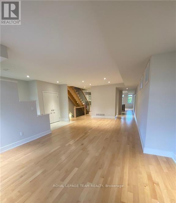 A spacious room with wooden flooring and white walls.