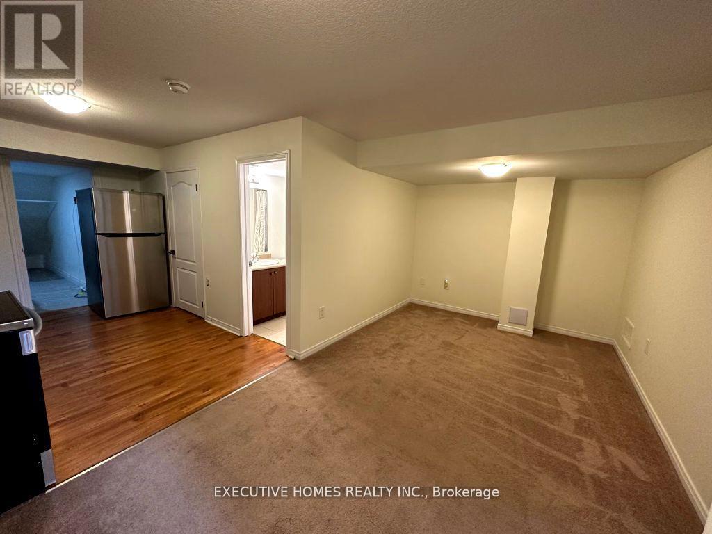 A spacious empty room with a refrigerator and a door leading to another room.
