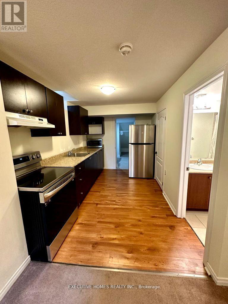 A kitchen with dark wood cabinets and a refrigerator in the background.