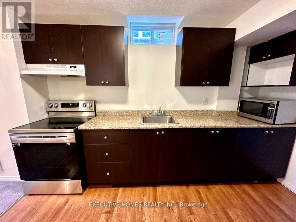 A kitchen with dark wood cabinets and a granite countertop.
