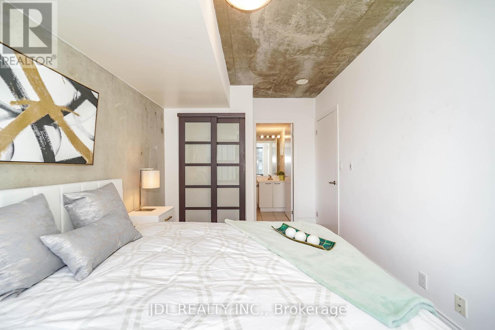 A bedroom with a large bed and a painting on the wall.