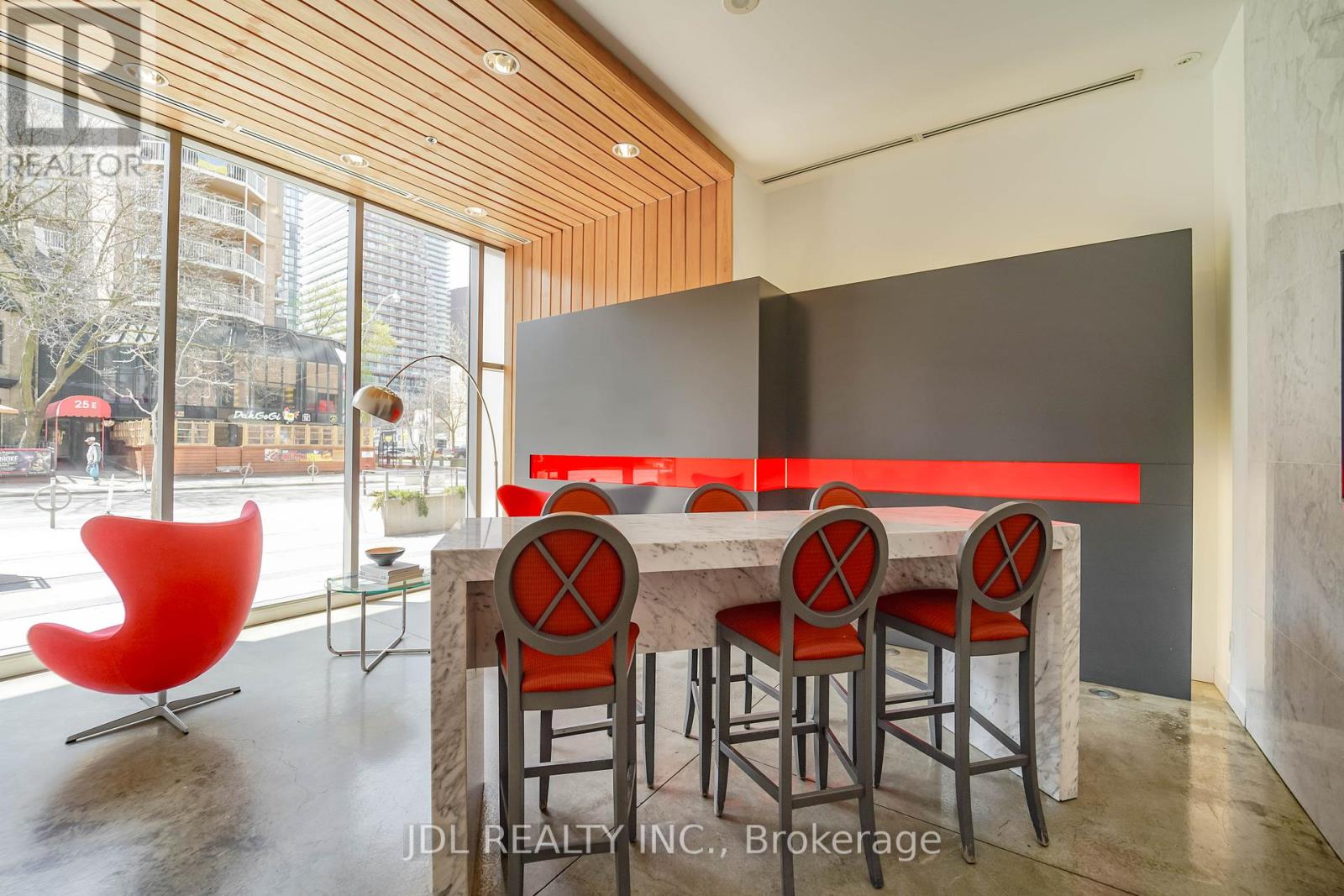 A modern dining room with a red chair and a table with four chairs.