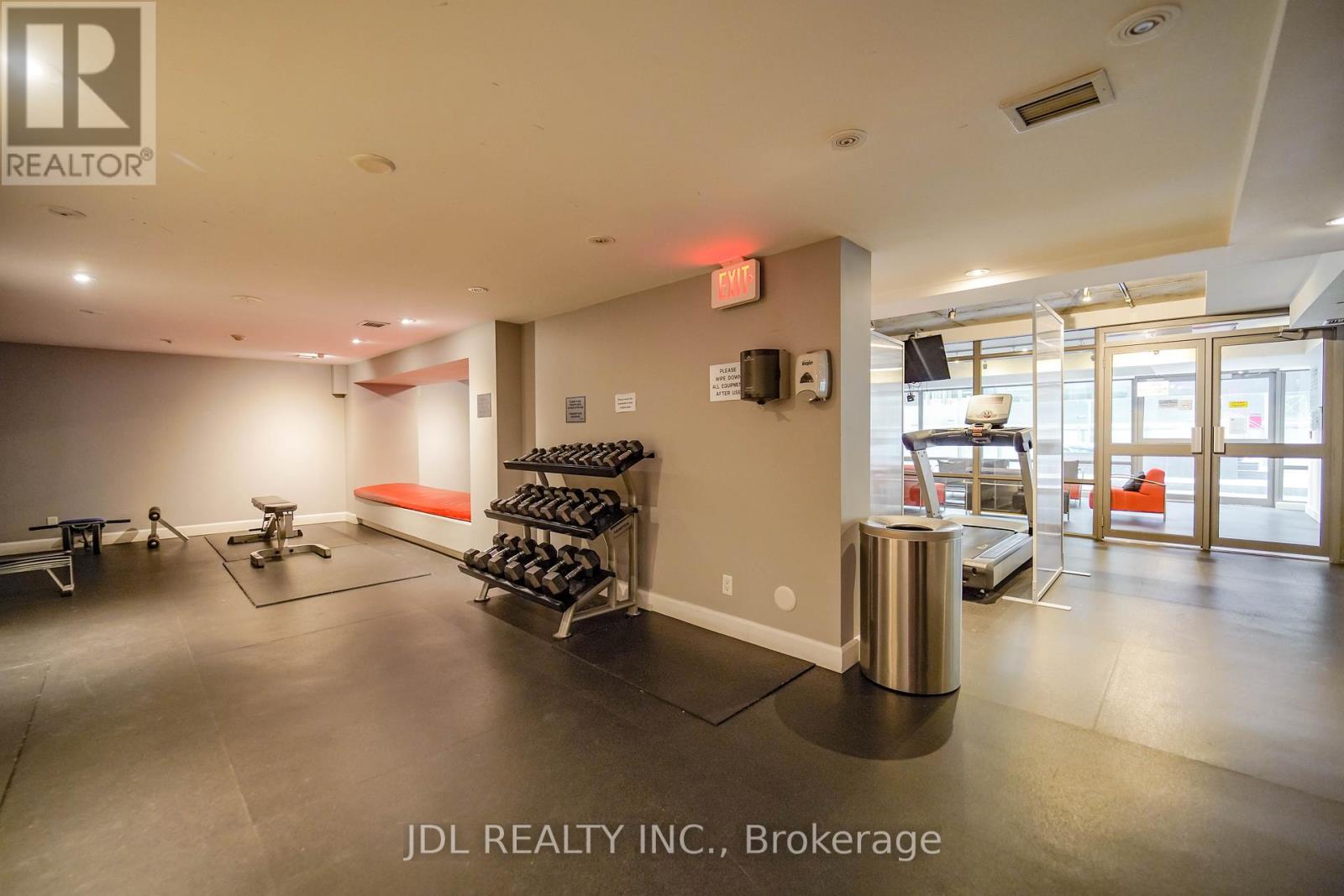 A gym room with a row of treadmills and weights.