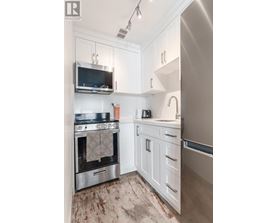 A modern kitchen with white cabinets and stainless steel appliances.