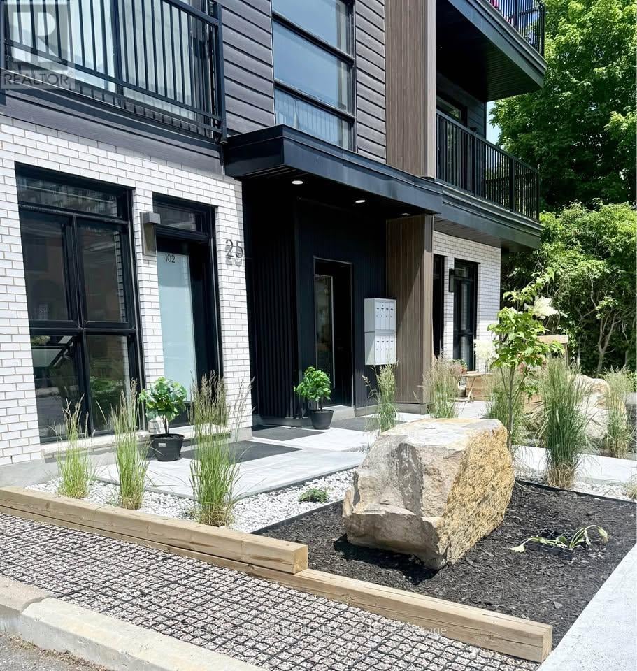 A modern house with a large rock in the front yard.