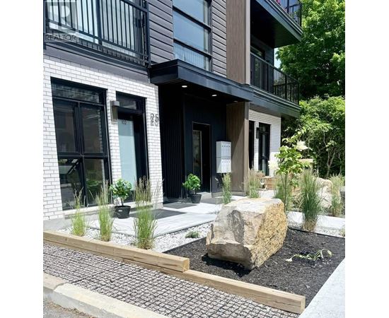 A modern house with a large rock in the front yard.
