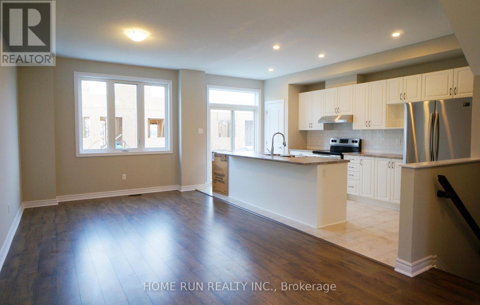 A real estate company is showcasing an empty kitchen and living room.