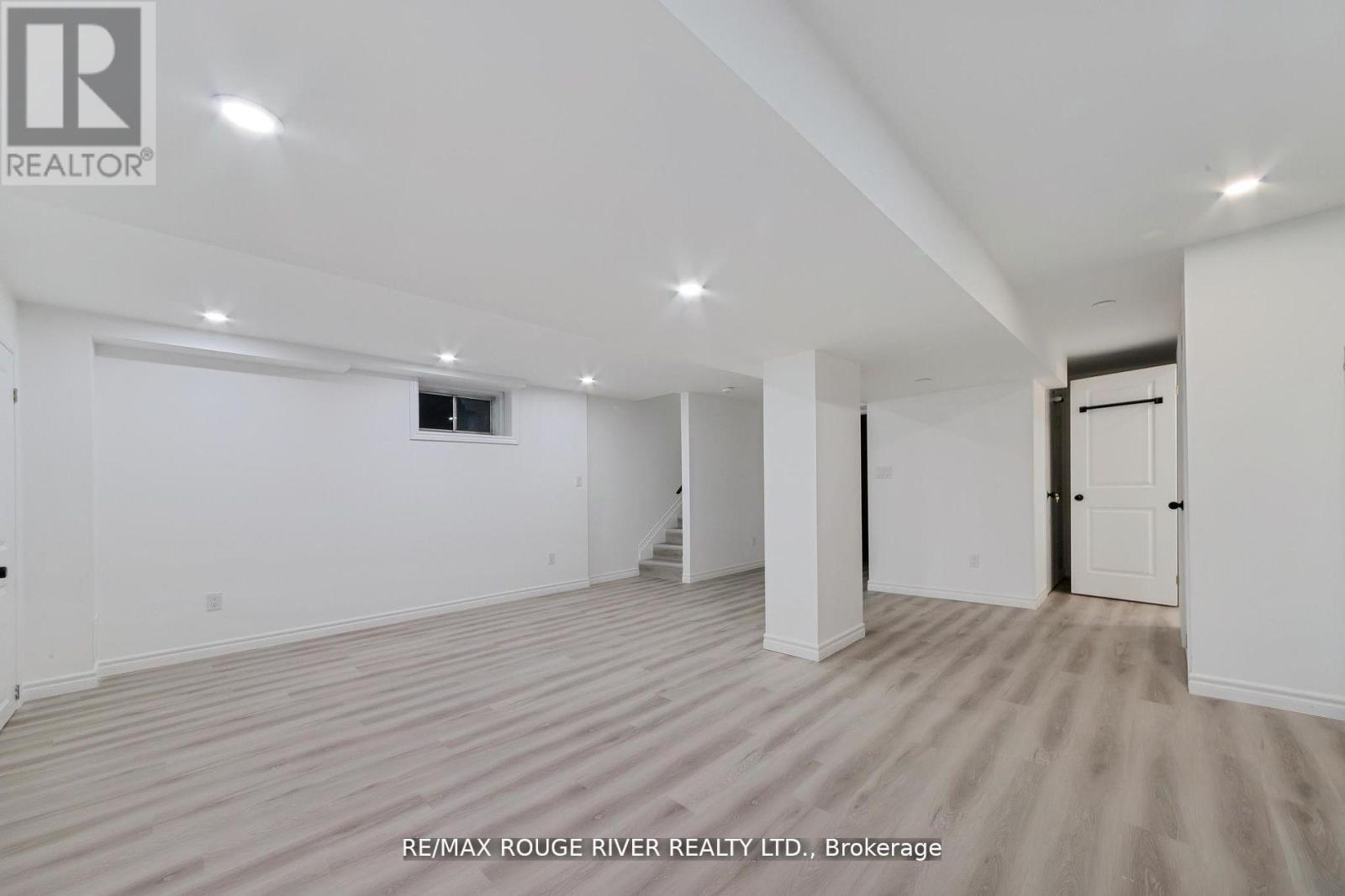A spacious room with beige carpeting and white walls, with a door on the right side.