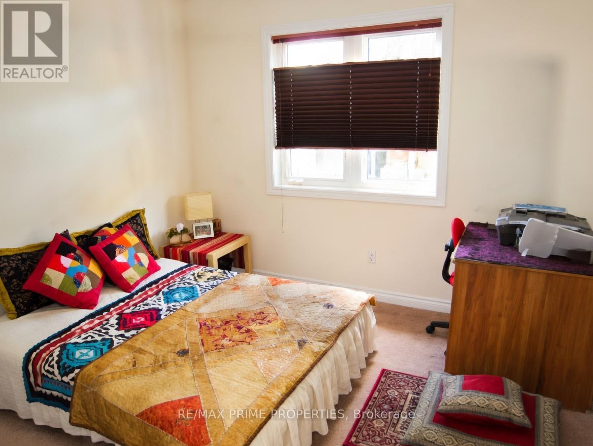 A bedroom with a bed covered in a quilt and a desk with a computer.