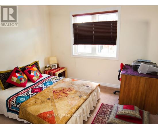 A bedroom with a bed covered in a quilt and a desk with a computer.
