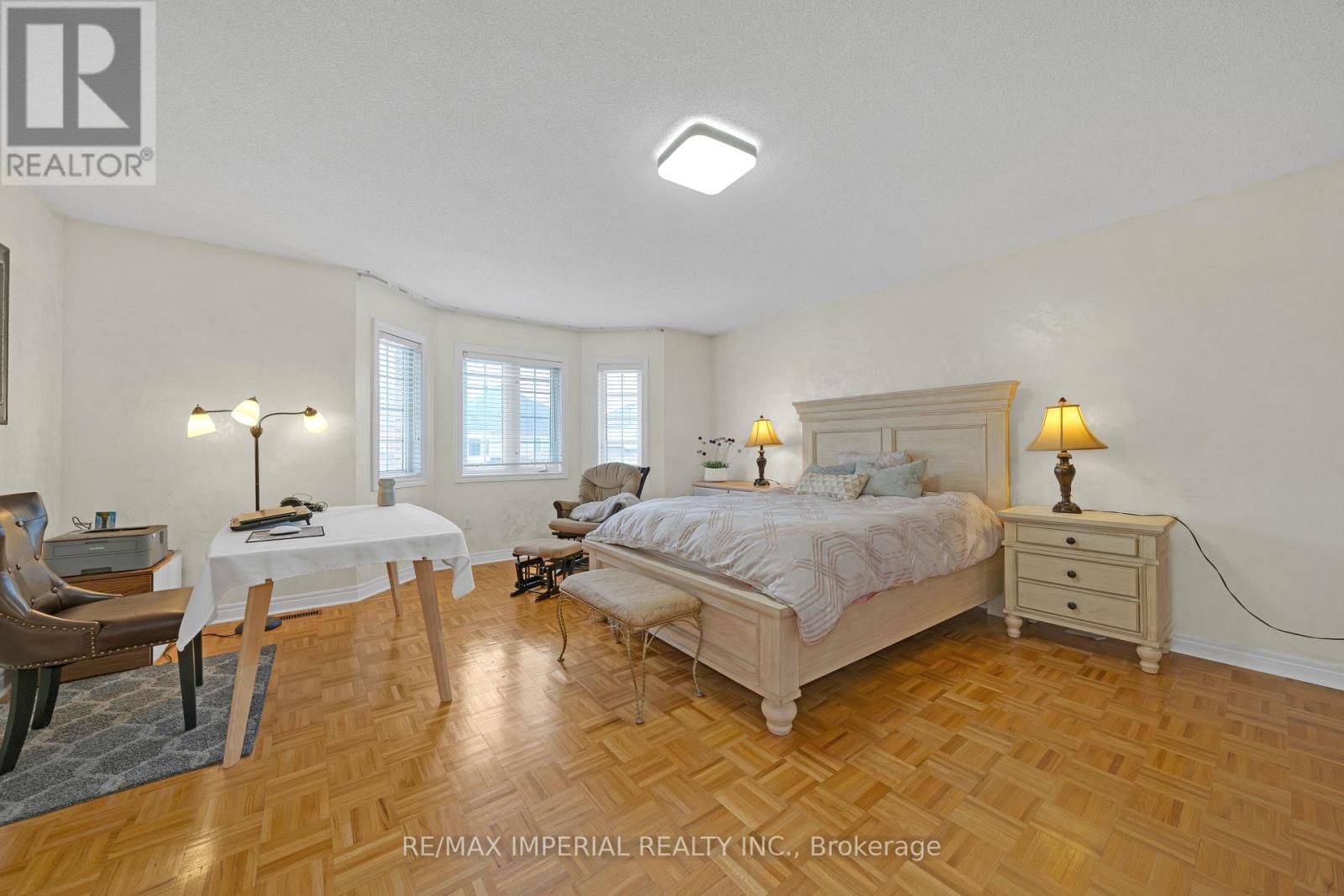 A bedroom with a large bed, a chair, and a table with a lamp on it.