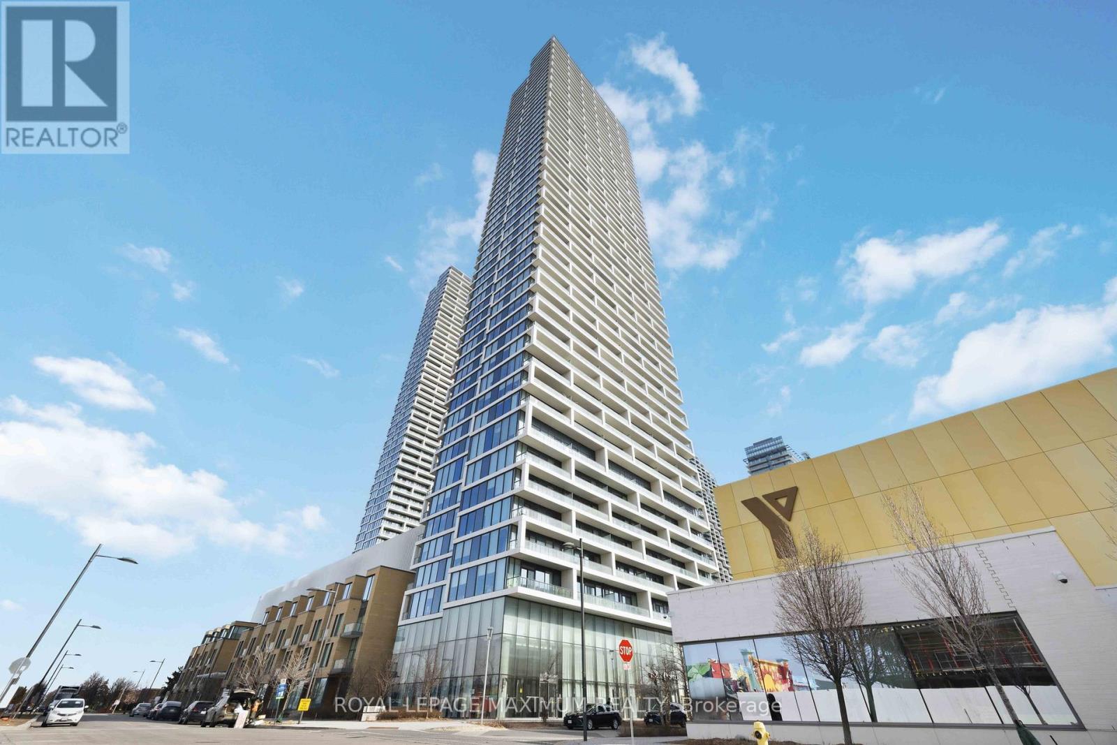 A tall building with a glass facade stands in front of a smaller building with a yellow facade.