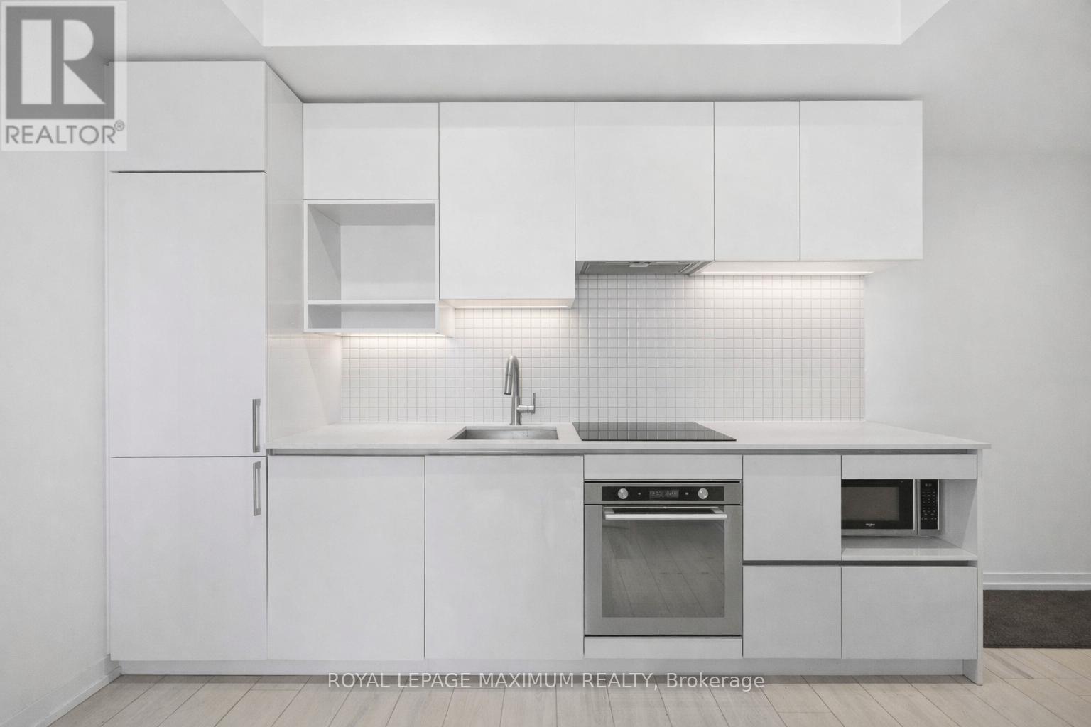 A white kitchen with a sink and a refrigerator.