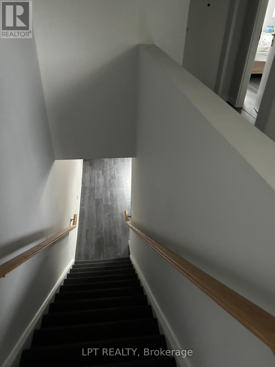 A staircase with a wooden handrail and black steps.