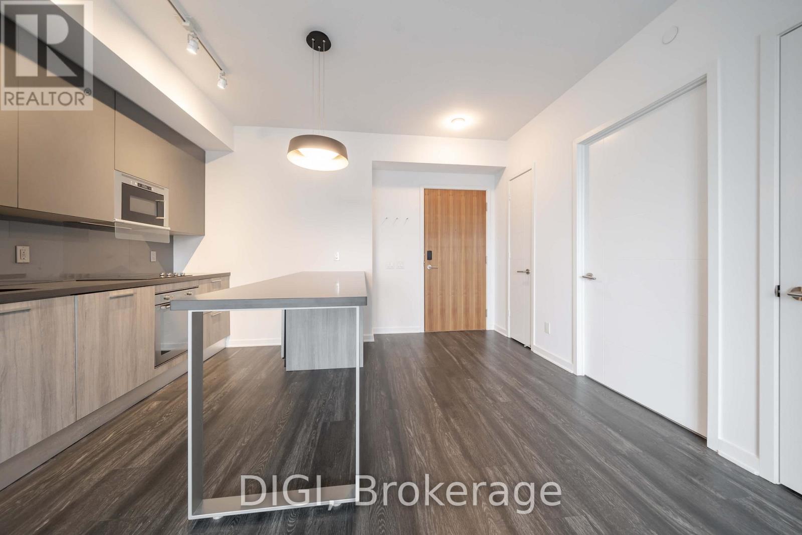 A modern kitchen with white cabinets and a wooden floor.