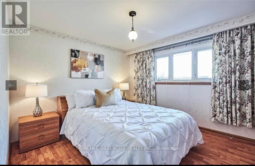 A bedroom with a bed, nightstand, and a picture on the wall.