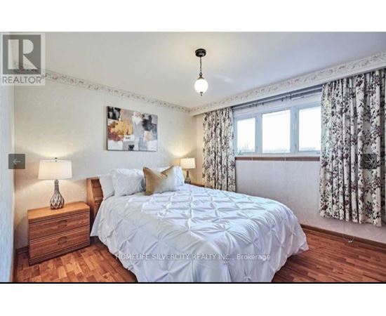 A bedroom with a bed, nightstand, and a picture on the wall.
