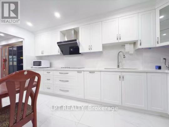 A kitchen with white cabinets and a wooden chair.