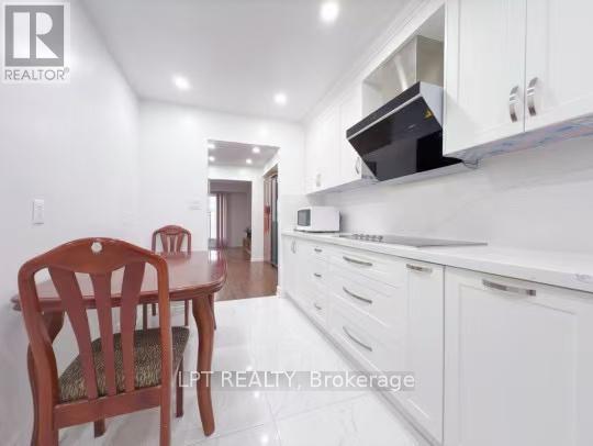 A kitchen with white cabinets and a wooden chair.