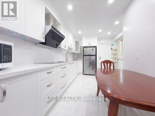 A kitchen with white cabinets and a wooden table.