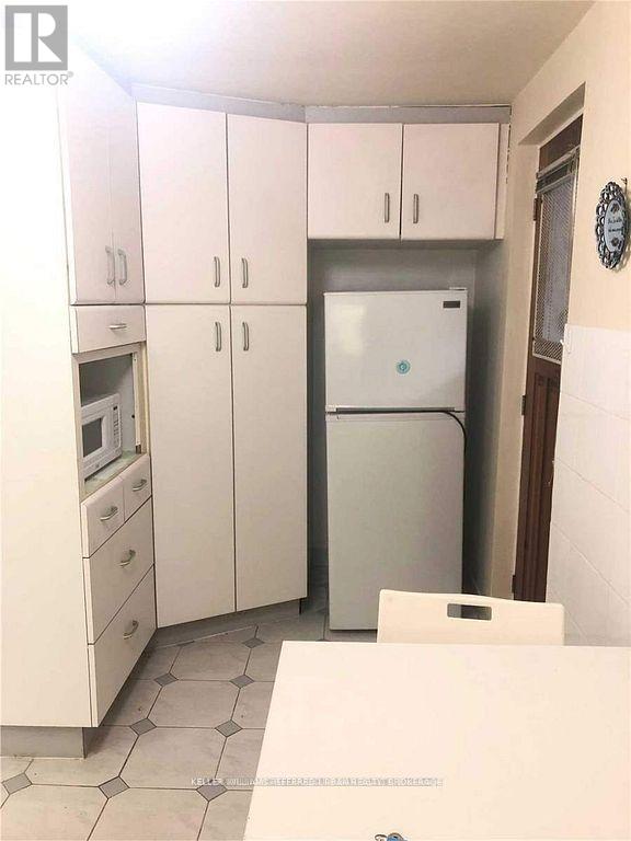 A kitchen with white cabinets and a fridge.