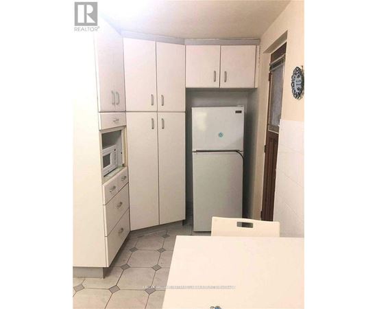 A kitchen with white cabinets and a fridge.