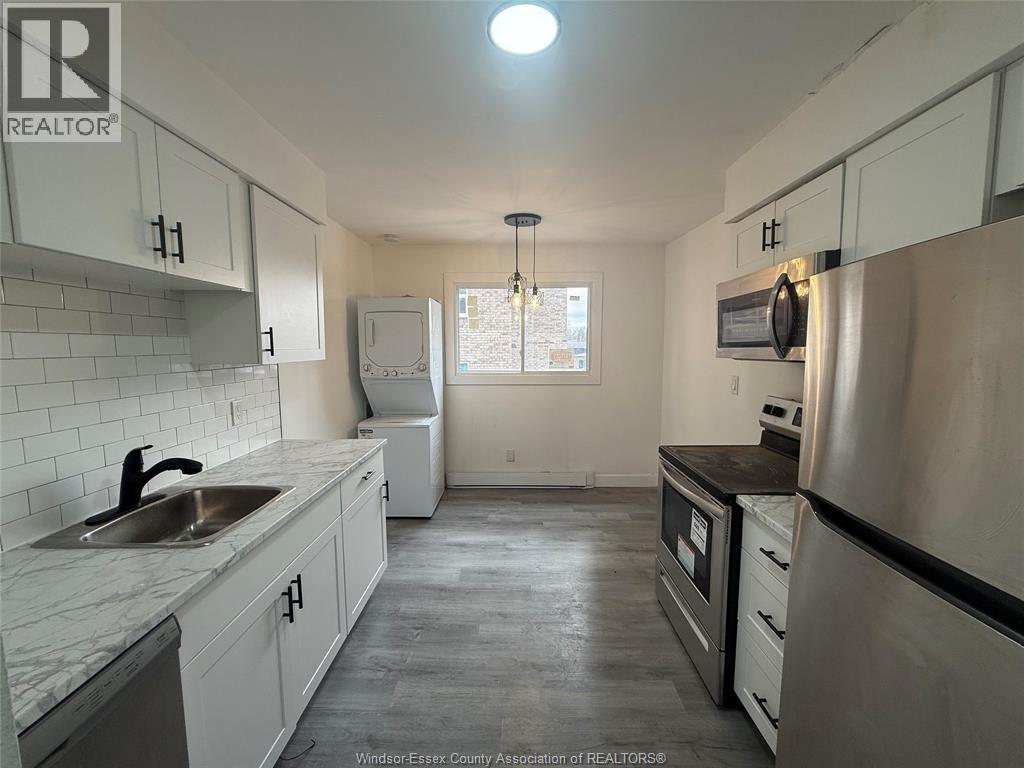 A kitchen with white cabinets and a stainless steel refrigerator.