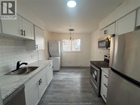 A kitchen with white cabinets and a stainless steel refrigerator.