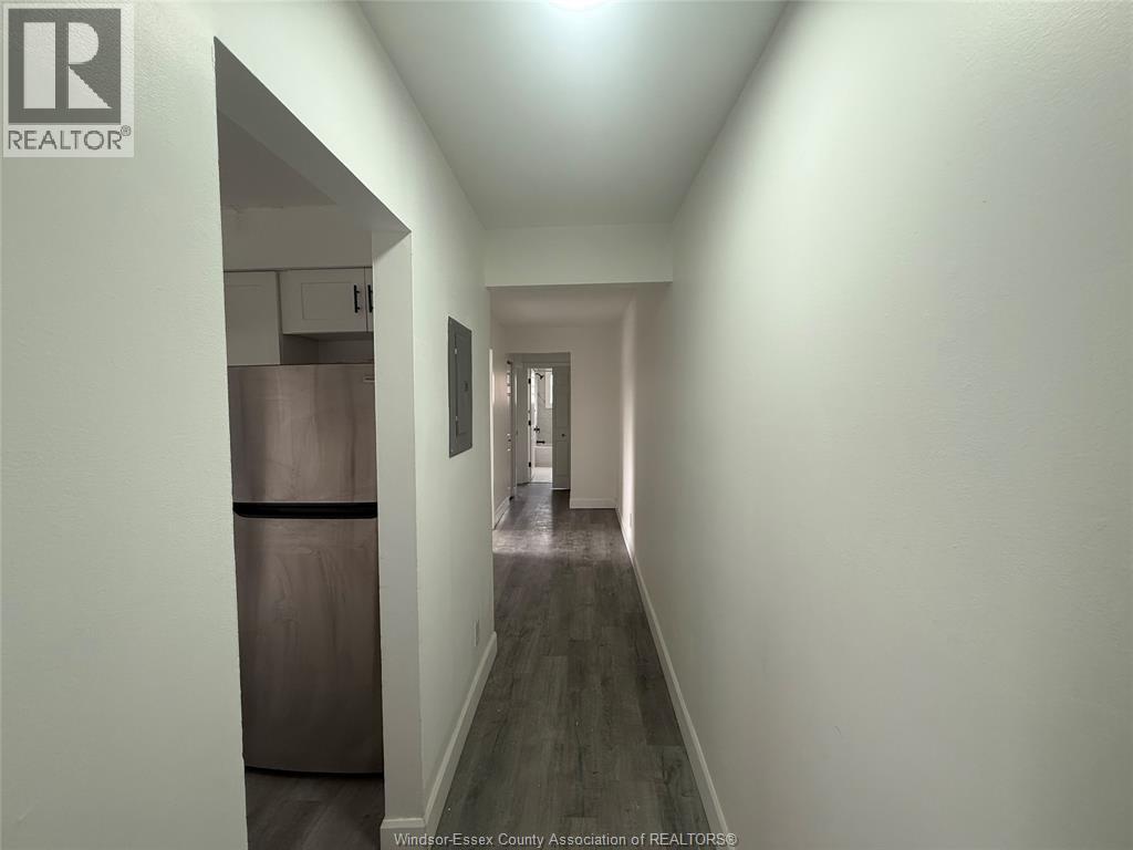 A long hallway with a refrigerator on the left and a door at the end.