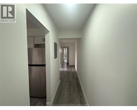 A long hallway with a refrigerator on the left and a door at the end.