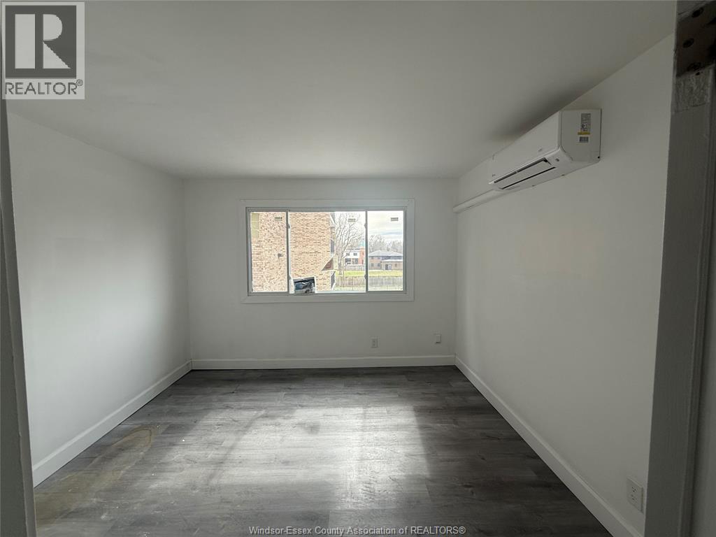 A room with a window and an air conditioner unit on the wall.