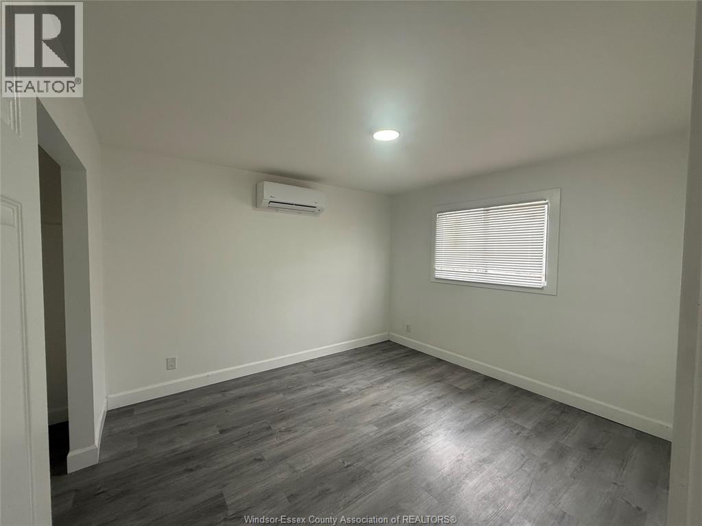 A room with a grey floor and a window with blinds.