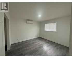 A room with a grey floor and a window with blinds.