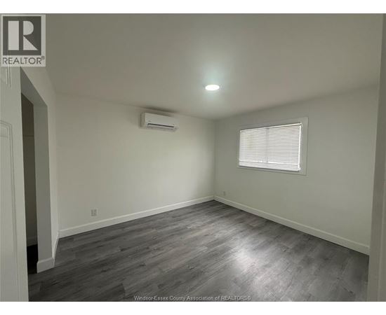 A room with a grey floor and a window with blinds.