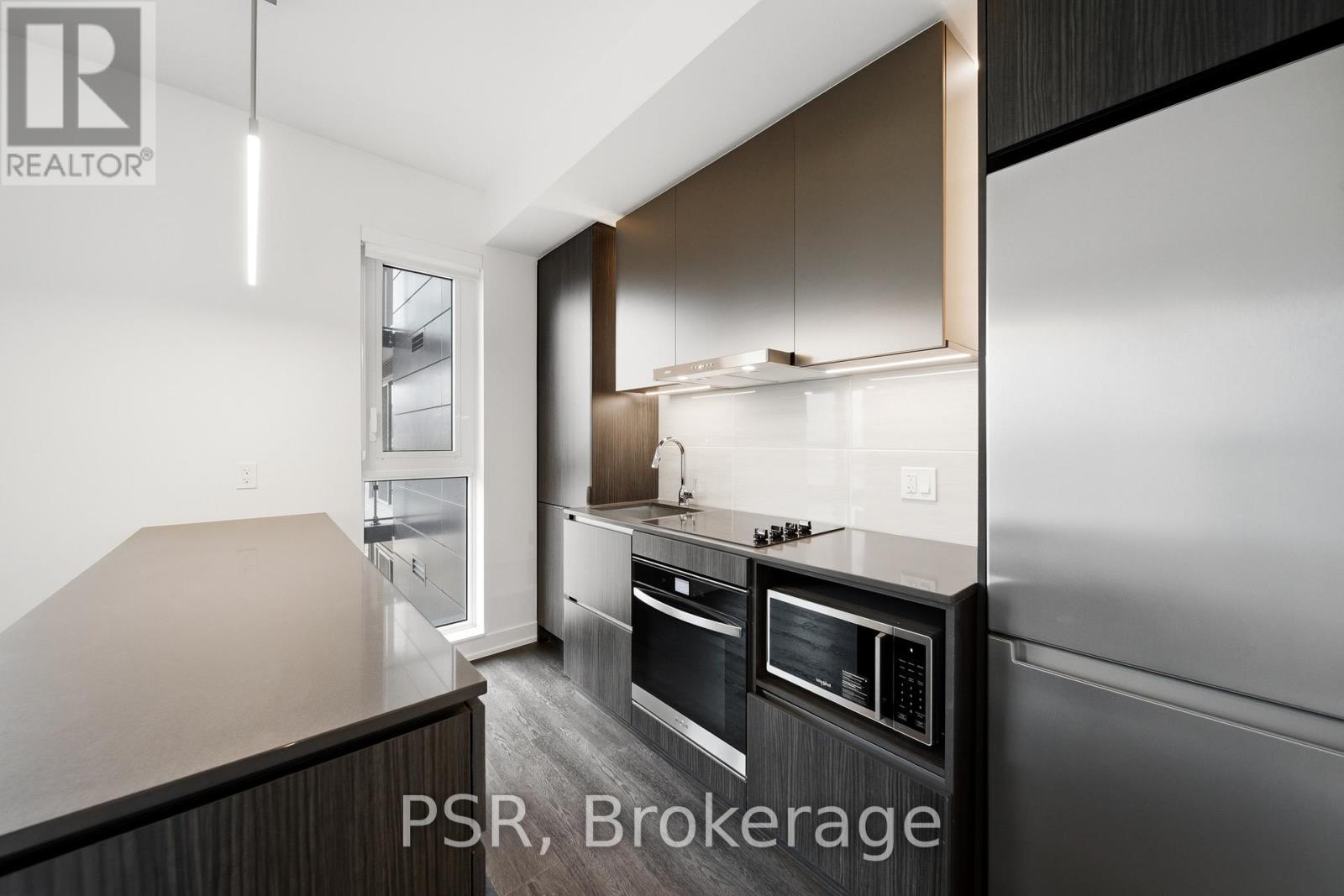 A modern kitchen with dark wood cabinets and stainless steel appliances.