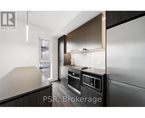 A modern kitchen with dark wood cabinets and stainless steel appliances.