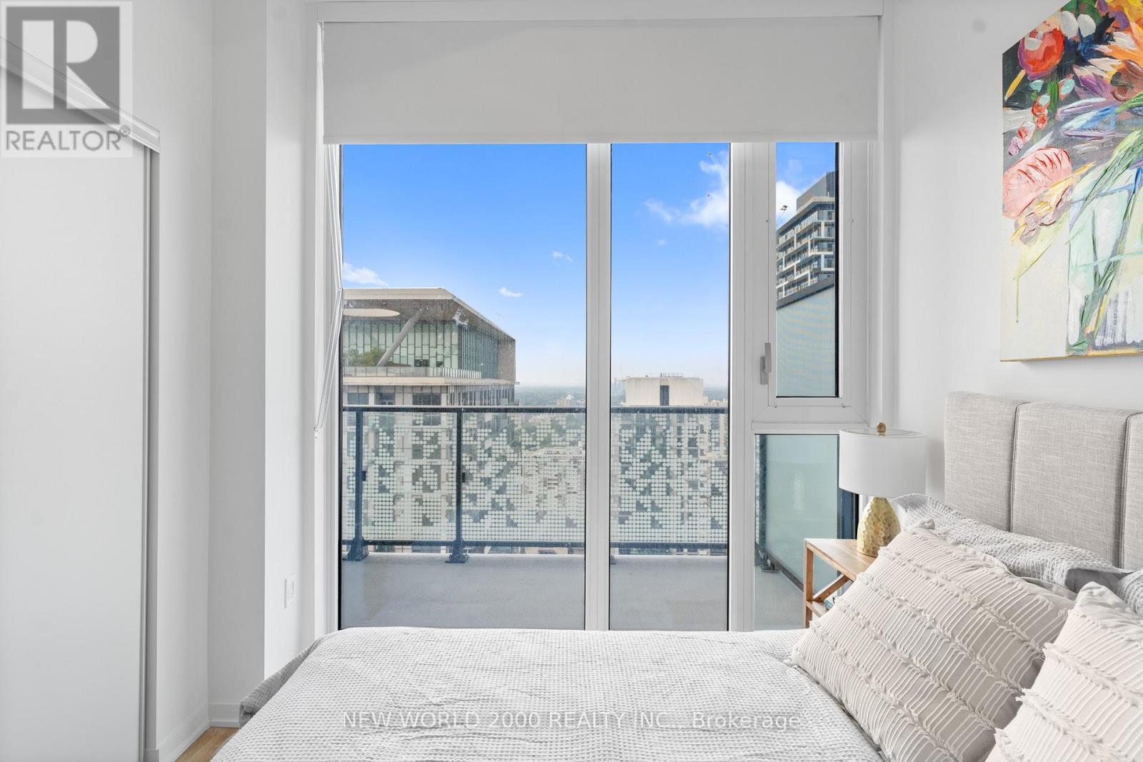A bedroom with a large bed and a view of the city through the window.