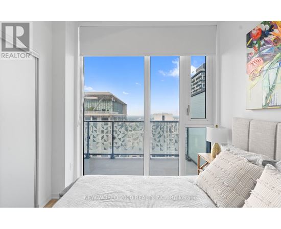 A bedroom with a large bed and a view of the city through the window.