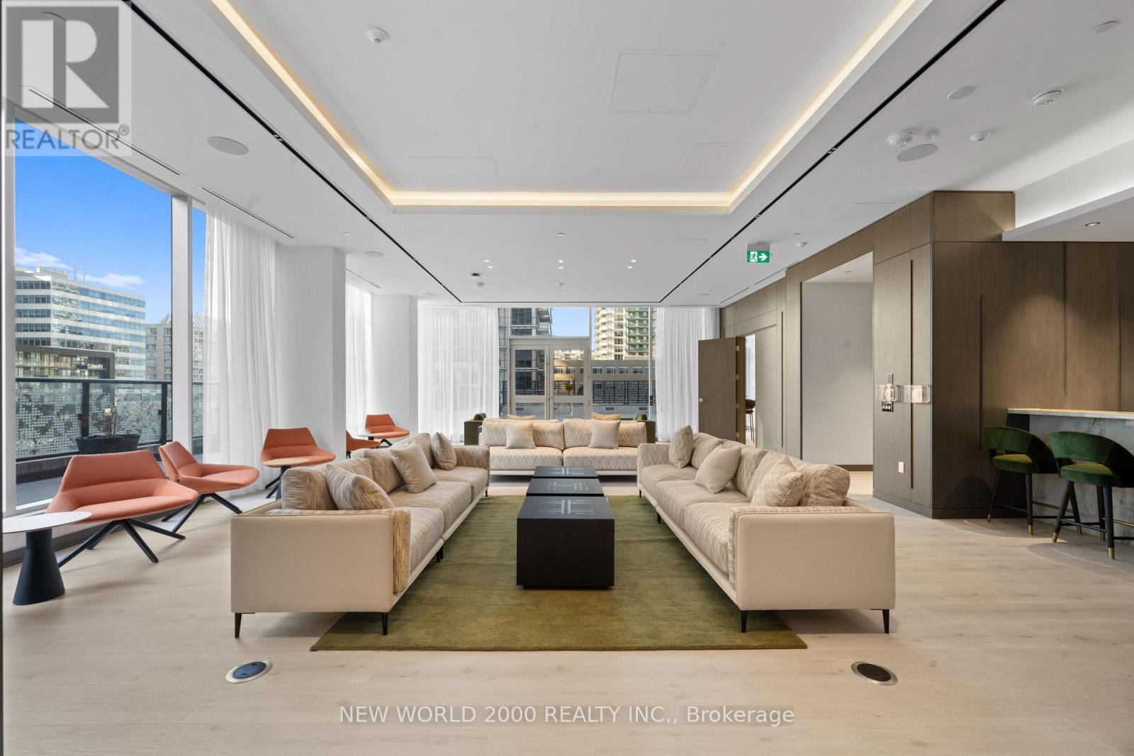 A spacious living room with a long white sofa and a green rug.