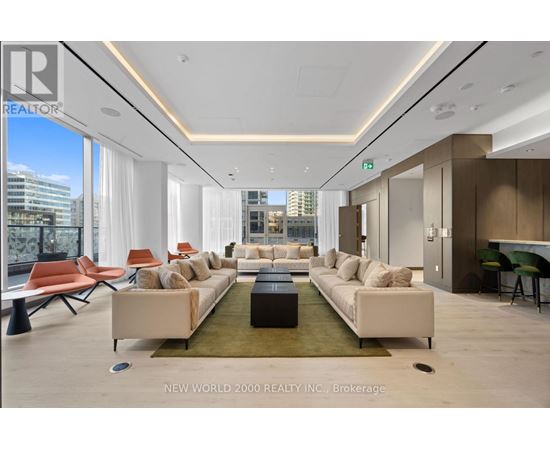 A spacious living room with a long white sofa and a green rug.