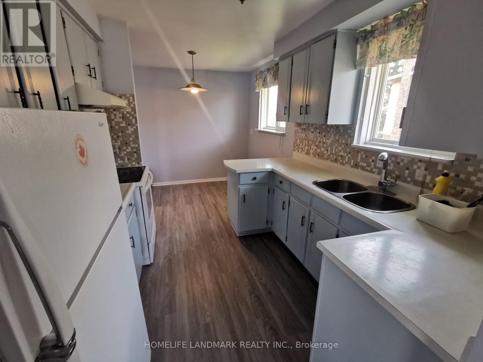 A kitchen with a white fridge and wooden floors.