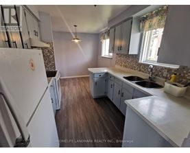 A kitchen with a white fridge and wooden floors.