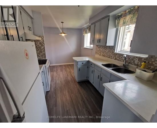 A kitchen with a white fridge and wooden floors.
