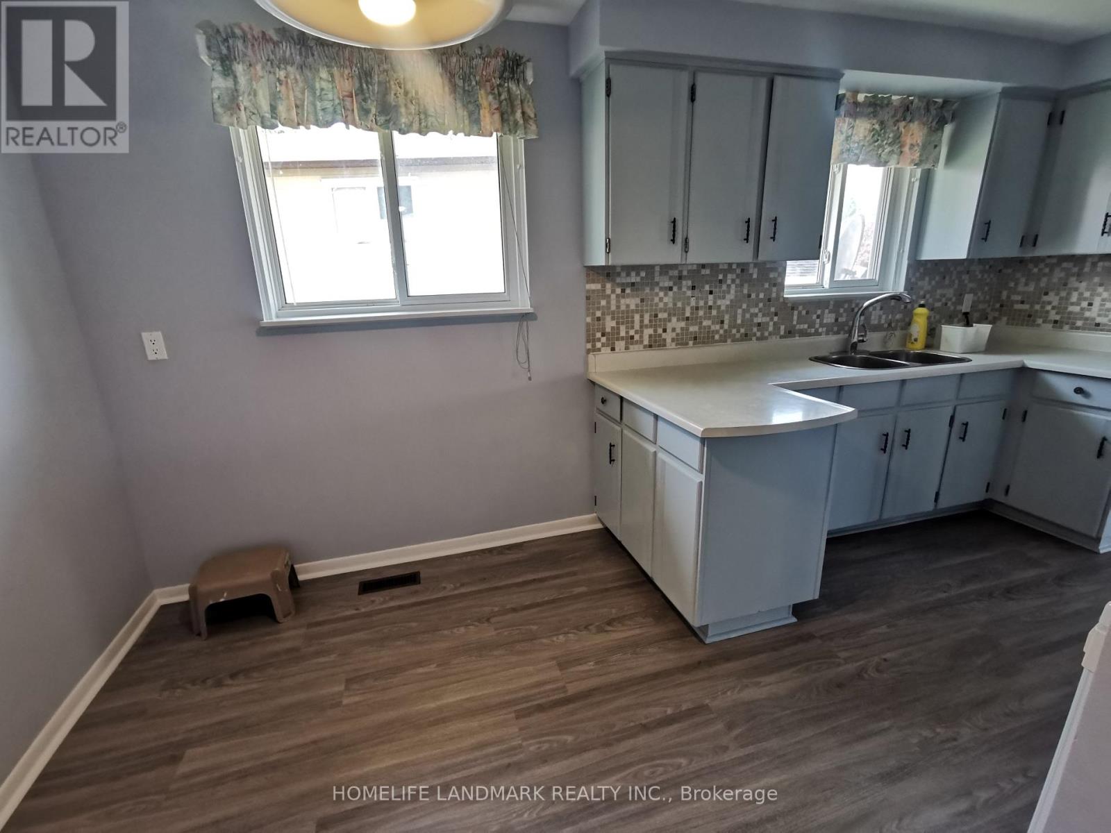 A kitchen with wooden floors and white cabinets.