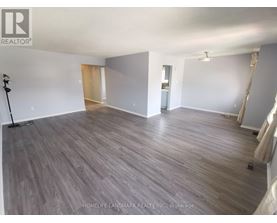 A spacious room with wooden flooring and white walls, likely for sale.