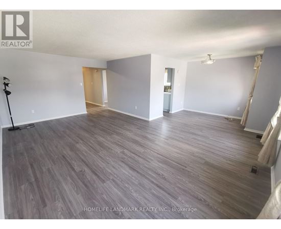A spacious room with wooden flooring and white walls, likely for sale.