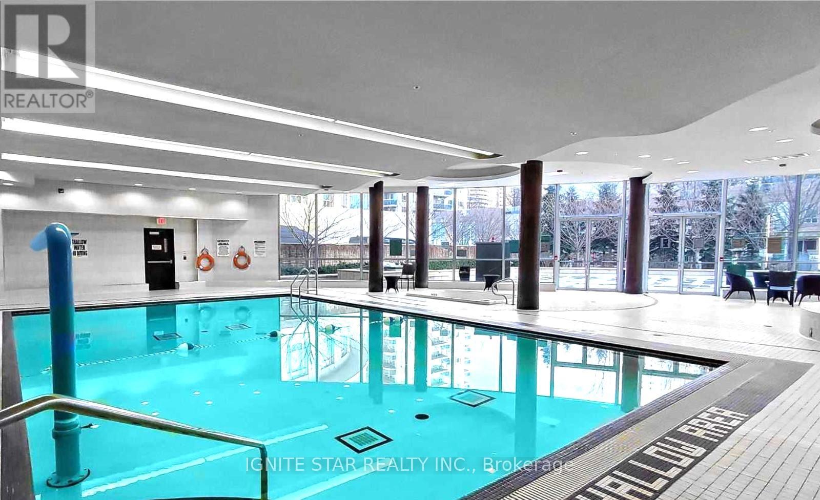 A large indoor swimming pool with a glass bottom and a sign that reads "Ignite Star Realty Inc., Brokerage.".