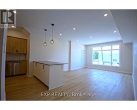 A large, empty room with wooden floors and a window overlooking a beach.
