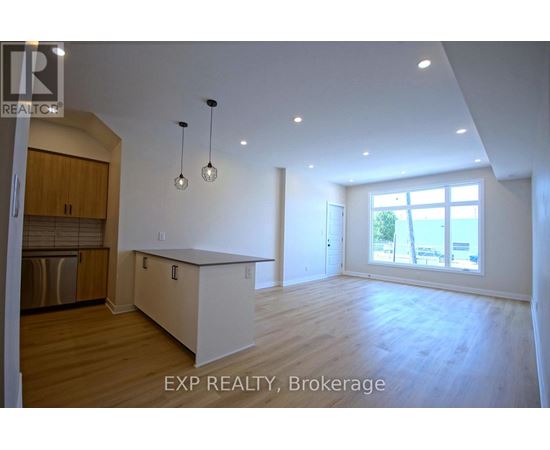 A large, empty room with wooden floors and a window overlooking a beach.